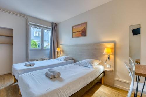 a hotel room with two beds and a desk at TERNELIA Le Vent Du Large in Saint-Gilles-Croix-de-Vie