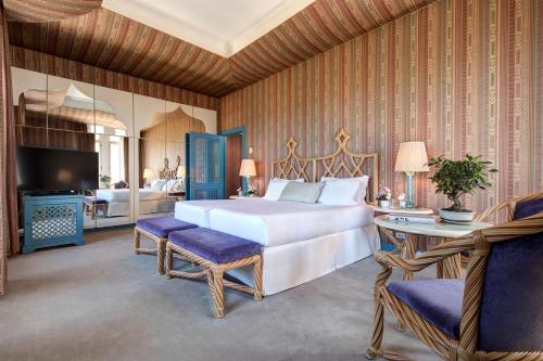 a bedroom with a bed and a table and a television at Hotel Excelsior Venice in Venice-Lido