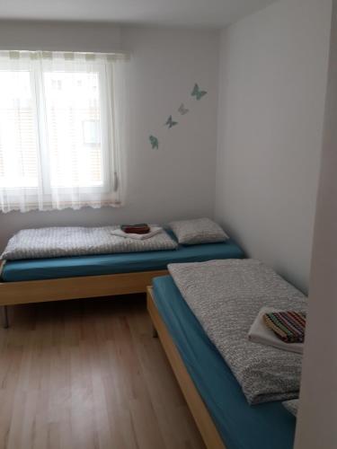2 Einzelbetten in einem Zimmer mit Fenster in der Unterkunft Ferienwohnung Sesvenna Davos in Davos