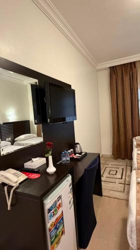 a hotel room with a desk with a tv on the wall at Miaad Al Majd Hotel in Mecca