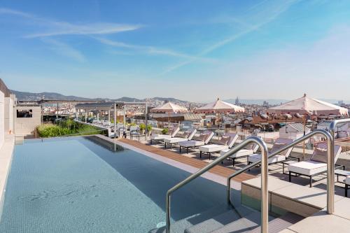 a swimming pool with lounge chairs and umbrellas at InterContinental Barcelona by IHG in Barcelona