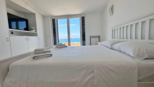 a white bedroom with a large bed with towels on it at Glory Guest House Sea View in Mandaradoni