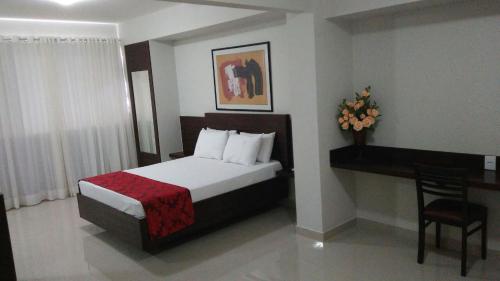 Habitación de hotel con cama, escritorio y cama sidx sidx en Center Patos Hotel, en Patos de Minas