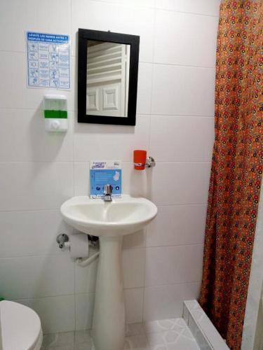 a bathroom with a sink and a toilet and a mirror at Casa hotel Comunicar Nini in Bogotá