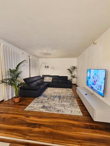 a living room with a black couch and a flat screen tv at Antica Dimora Confine in Mira