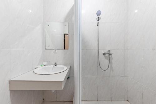 a white bathroom with a sink and a shower at Urbanview Hotel Tridaya Cisarua Puncak in Kopo 2
