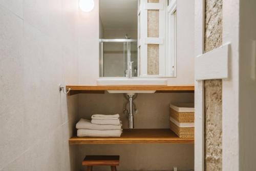 a bathroom with a sink and towels on a shelf at Apartamentos Turísticos - ELBUZONROJO in Burgos
