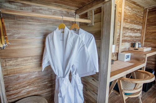 a white shirt hanging on a wooden wall at The Old Island Huts in Nusa Lembongan