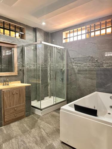a bathroom with a shower and a tub and a sink at AMINA luxury SUITE in Lomé