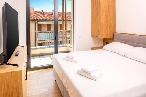 a bedroom with a white bed and a large window at The Penthouse Bardolino in Bardolino