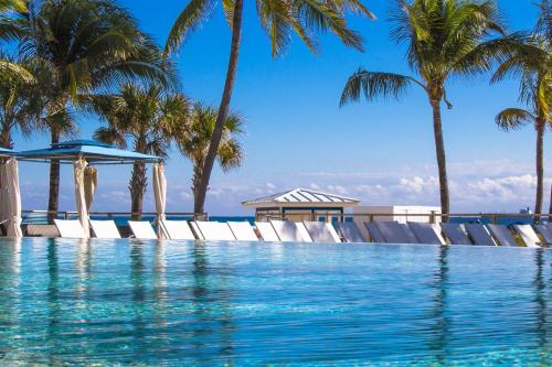 a swimming pool with chairs and palm trees at B Ocean Resort in Fort Lauderdale