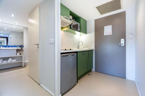 a kitchen with green and white cabinets and a sink at Privilège Appart Hôtel Saint Exupéry in Toulouse