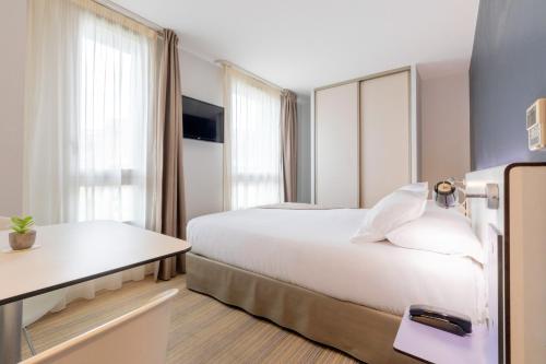 a hotel room with a large white bed and a table at Privilège Appart Hôtel Saint Exupéry in Toulouse