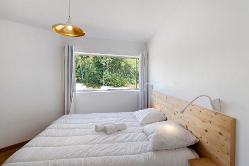 a white bedroom with a large bed and a window at Gite Design La Station in Angoisse