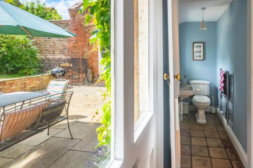 a door leading to a patio with a toilet and a sink at Laylands in Wells next the Sea
