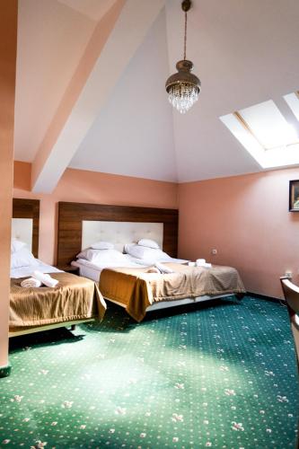 two beds in a room with green carpet at Rezydencja Jagiellońska in Sanok
