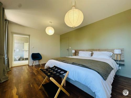 a bedroom with a large bed and a chair at La Ferme de Sainte Isabelle in Montlay-en-Auxois