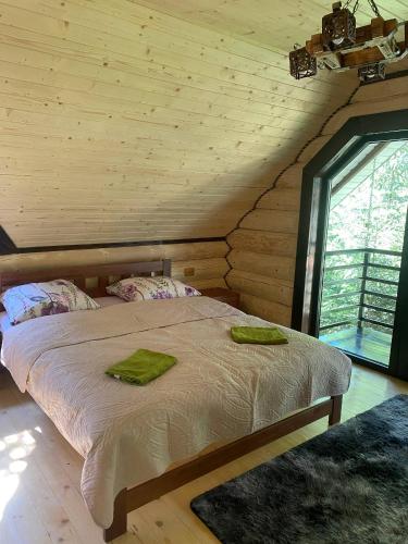 a bedroom with a bed with two green towels on it at Подих Лісу 2 in Synevyrsʼka Polyana