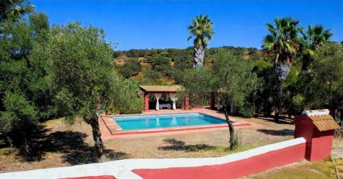a swimming pool in the middle of a yard with trees at Villa Rural Las Encinas in Alosno