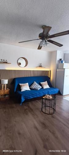 a living room with a blue couch and a ceiling fan at Studio 4 personnes au Cap-d'Agde in Agde