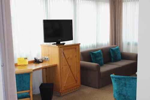a room with a couch and a television on a desk at Hotel Landhaus Feckl in Böblingen