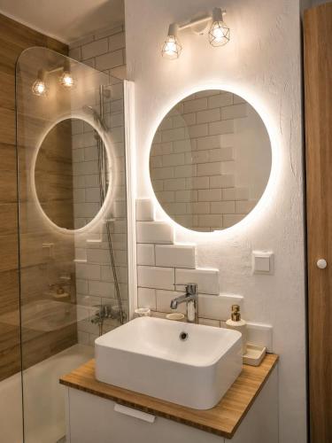 a bathroom with a white sink and two mirrors at Hanga Apartman in Băile Tuşnad