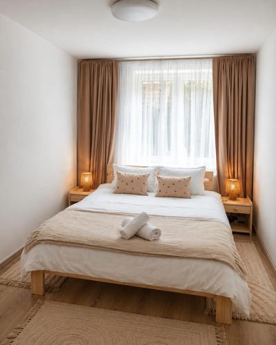 a bedroom with a large bed with a window at Hanga Apartman in Băile Tuşnad