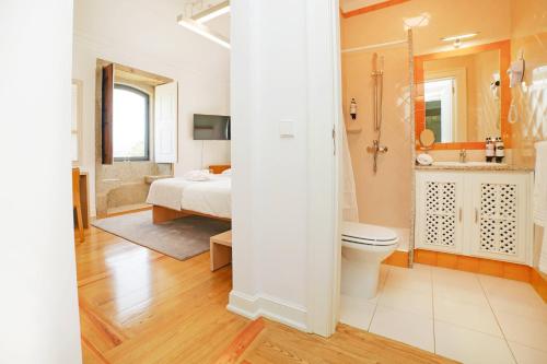 a bathroom with a toilet and a bed and a shower at Solar das Bouças by Quantique in Amares