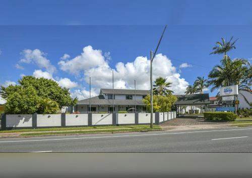 an empty street with a white fence and a building at Alara Motor Inn in Mackay