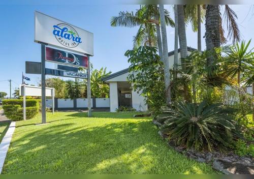 a sign in front of a building with palm trees at Alara Motor Inn in Mackay