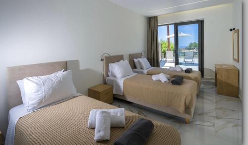 a hotel room with two beds and a balcony at Phoenix Coastal Heaven in Loutro