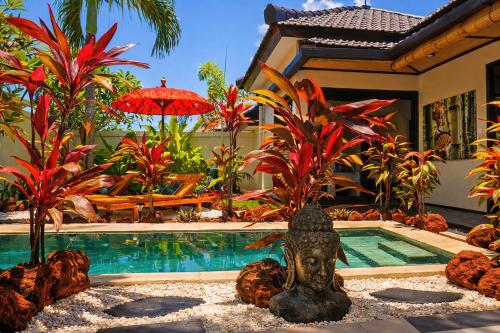 a pool with a statue in front of a house at Hakuna Matata Bali Villas in Uluwatu
