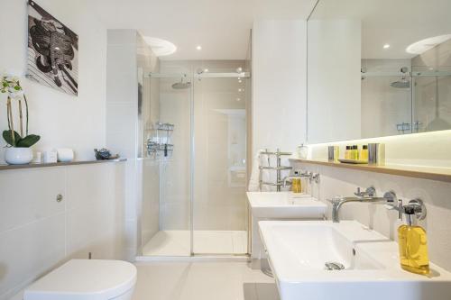 a white bathroom with two sinks and a shower at 8 Salt in St Ives