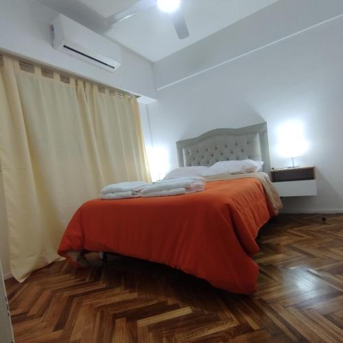 a bedroom with a bed with an orange blanket at alma in Buenos Aires