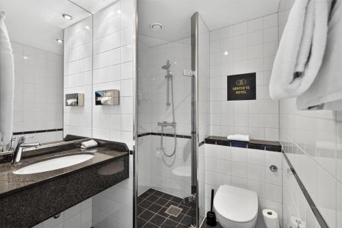 a bathroom with a shower and a toilet and a sink at Gentofte Hotel in Gentofte