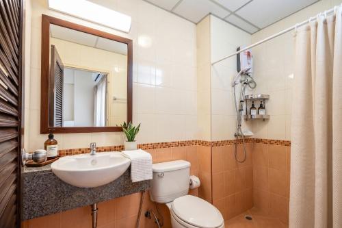 a bathroom with a sink and a toilet and a mirror at K.V.Mansion in Bangkok