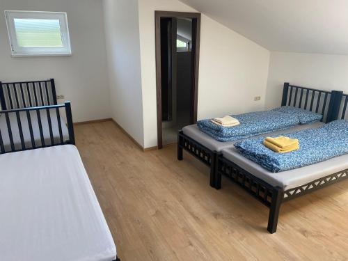two beds sitting in a room with wooden floors at 3 Elementy in Čachtice