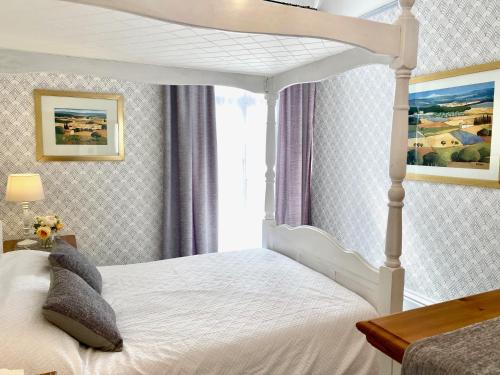 a bedroom with a white bed with a canopy at Simply the best ! 4 Min walk to Beach, Pubs, Restaurants, Shops, Heated Pool, Hottub, Games room, 1 acre Garden, BBQ's, Private Parking, WIFI, Basesets acre, call for other dates ! in Portreath