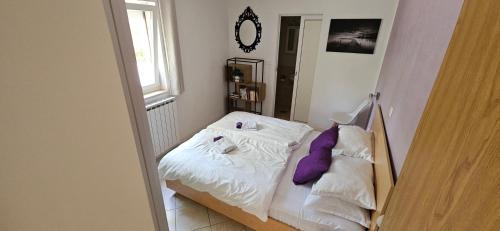a small bedroom with a bed with purple pillows at Luxury Flat with Heated Pool & Jacuzzi in Rijeka