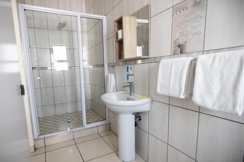 a white bathroom with a shower and a sink at Ecotel Southgate in Southgate