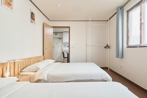 a bedroom with two beds and a window at Travel Home in Seoul
