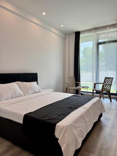 a bedroom with a large bed and two chairs at Mimar Boutique in Eforie Sud