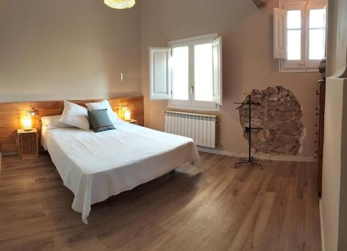a bedroom with a bed and two windows at Cal NEN PAU in Sant Boi de Lluçanès