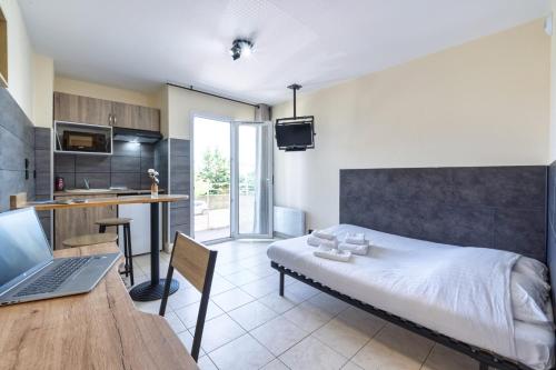 a bedroom with a bed and a laptop on a table at Résidence Columba - Apparts meublés Agen Sud in Agen