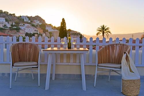 a table and two chairs on a balcony with a fence at Unique luxury suites in Hydra