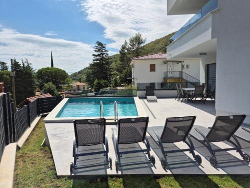 a backyard with a swimming pool and chairs and a house at Villa Aylen in Mošćenička Draga