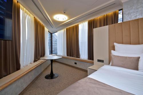 a hotel room with a bed and a table and windows at Nord Gate Avenue Hotel in Yerevan
