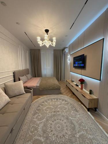 a bedroom with a couch and a bed and a television at Жк Prime Park 2 in Shymkent