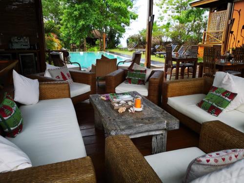a patio with wicker chairs and a table and a pool at Villa Vanilla in Port Glaud