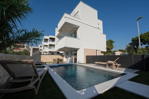 a white house with a swimming pool and two chairs at Smash A - Apartments with Private Pool in Novalja
